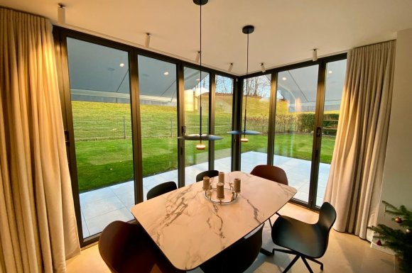 Splendide extension de pièce de vie réalisée grâce à une baie accordéon d’angle, offrant une ouverture maximale sur l’extérieur.