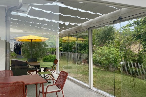 Installation d’une toiture vitrée sur-mesure et de coulissants pivotants : élégance et transparence pour une charmante maison dans l’Ain (01)