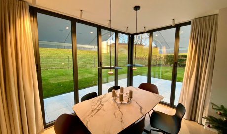 Splendide extension de pièce de vie réalisée grâce à une baie accordéon d’angle, offrant une ouverture maximale sur l’extérieur.