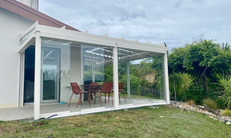 Installation d’une toiture vitrée sur-mesure et de coulissants pivotants : élégance et transparence pour une charmante maison dans l’Ain (01)