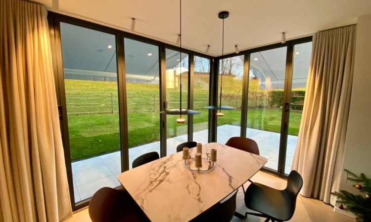 Splendide extension de pièce de vie réalisée grâce à une baie accordéon d’angle, offrant une ouverture maximale sur l’extérieur.