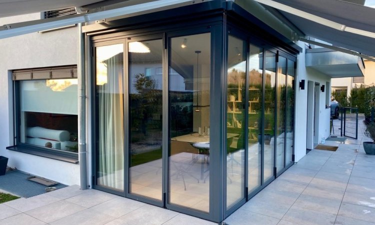 Splendide extension de pièce de vie réalisée grâce à une baie accordéon d’angle, offrant une ouverture maximale sur l’extérieur.