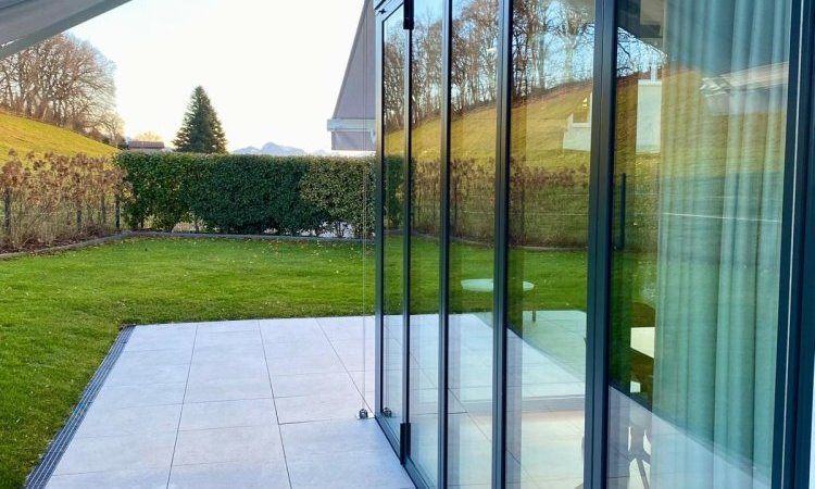 Splendide extension de pièce de vie réalisée grâce à une baie accordéon d’angle, offrant une ouverture maximale sur l’extérieur.