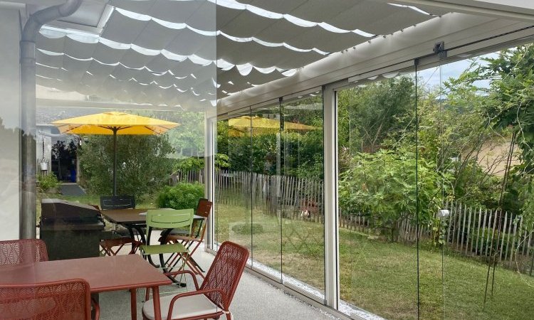 Installation d’une toiture vitrée sur-mesure et de coulissants pivotants : élégance et transparence pour une charmante maison dans l’Ain (01)